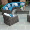 Outdoor patio sectional set with blue cushions, wicker frames, coffee table, and accent pillows on stone flooring.