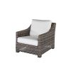 Woven wicker club chair with white cushions in hickory finish.