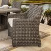 Wicker dining arm chair with cushion at an outdoor table beside a pool.