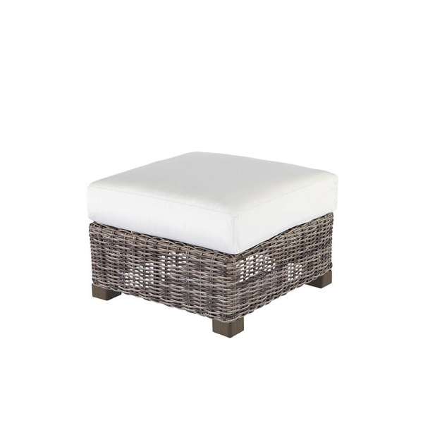 Woven wicker ottoman with white cushion in hickory finish.