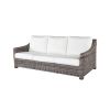 Woven wicker three-seat sofa with white cushions in hickory finish.