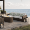 Outdoor wicker XL sofa with cushions on resort patio deck by the ocean with fire pit