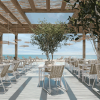 Cabana woven dining side chairs in Barley and Bone finish set at white dining tables in a beachfront restaurant.