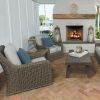 Laurent wicker club chairs with light cushions arranged by an outdoor fireplace.