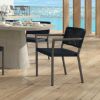 Orleans woven dining arm chair in Coal Smoke finish by an outdoor poolside dining table.