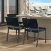 Pair of Orleans woven dining side chairs in Coal Smoke finish at an outdoor dining table by the pool.