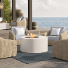 Ivory Bellino fire pit table on a seaside patio with wicker chairs and ocean view