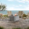 Outdoor setup with Bellino 42" round patio fire pit table by the ocean and lounge chairs