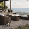 Outdoor wicker seating set with oval Hampton patio fire pit table on deck overlooking the ocean.
