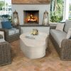 Light shell finish Tahoe patio coffee table styled with wicker furniture and fireplace