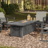 70" × 32" XL Trevi Fire Pit Patio Table with Graphite Finish surrounded by lounge chairs in a garden setting