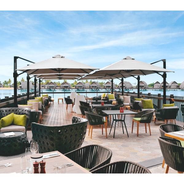 Eclipse 10 foot square aluminum cantilever umbrellas shading resort poolside dining area with commercial outdoor tables and chairs