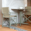 Boss folding sling dining chairs with tan fabric and green polypropylene frames paired with a café table in a modern dining setting