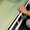 Worker installing new sling fabric on a commercial pool chaise lounge