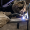 Close-up of a minor weld repair being performed on a commercial pool furniture frame