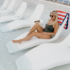 Woman relaxing on a white Forma chaise lounge on a shallow swimming pool tanning ledge