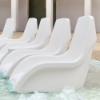 White Forma in-pool chairs arranged on a shallow swimming pool tanning ledge
