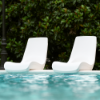 Two white Forma pool edge seat chairs positioned beside a commercial swimming pool