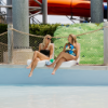 Two guests relaxing on white Forma pool edge seat chairs beside a commercial pool