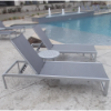 20-inch Coastal round aluminum patio side table between sling chaise lounges on a commercial pool deck