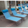 Urban stackable aluminum sling chaise lounges with blue fabric arranged on a commercial pool deck