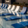 Aqua MGP in-pool chaise lounges arranged on a shallow swimming pool sun shelf in blue and white finishes