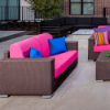 Java Chocolate wicker outdoor patio love seat with bright pink cushions and blue accent pillows in a commercial patio setting