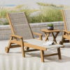 Polywood Coastal sling chaise with wheels featuring a teak-colored frame and neutral sling on an outdoor coastal patio