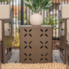 16" square commercial side table with decorative flower cutouts positioned between cushioned patio chairs in an outdoor seating area